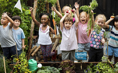 Lots of happy children learning about sustainability in a garden at Little Lights Childcare