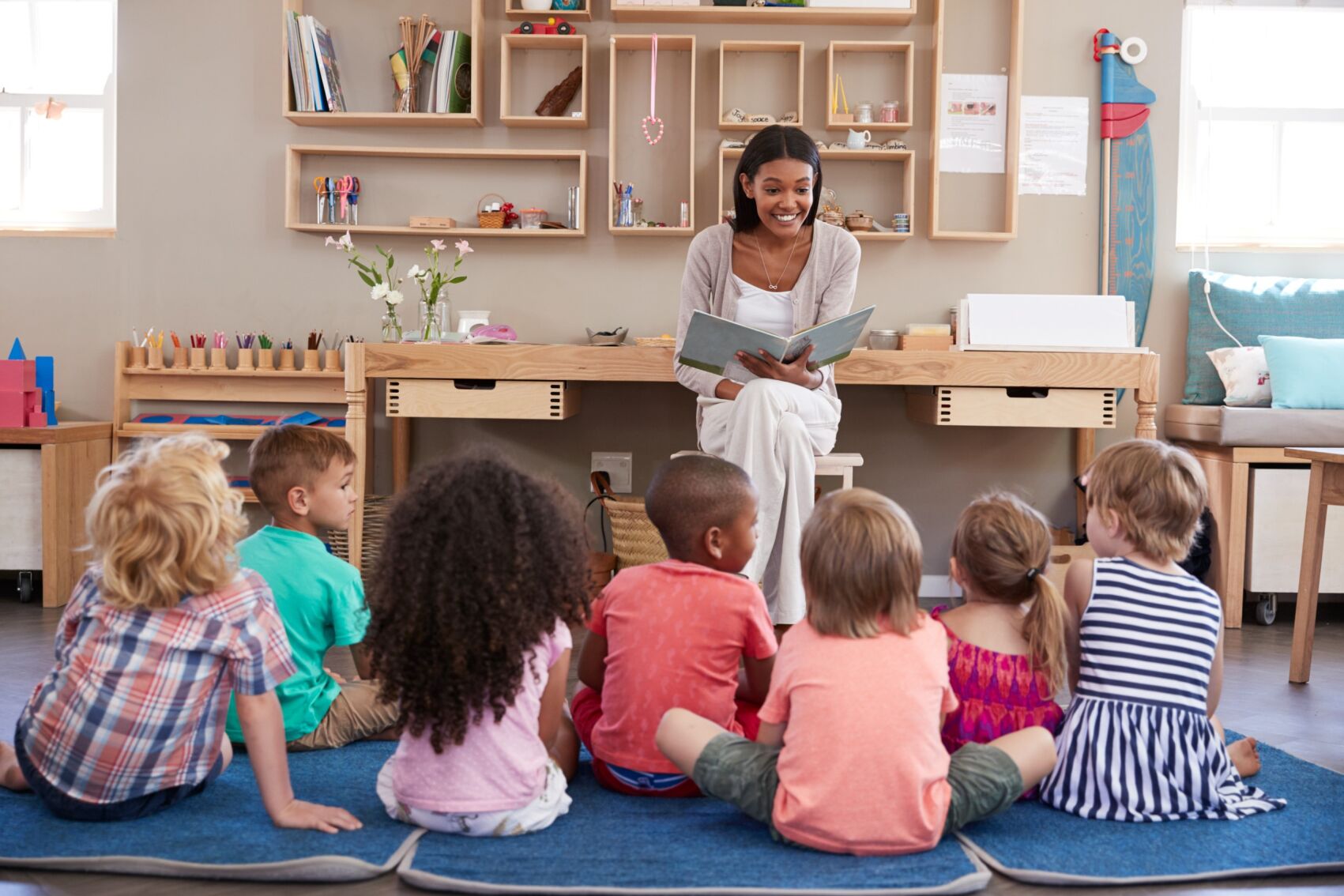 Children sitting on the floor attentively listening to a story being read by a teacher at Little Lights Childcare.